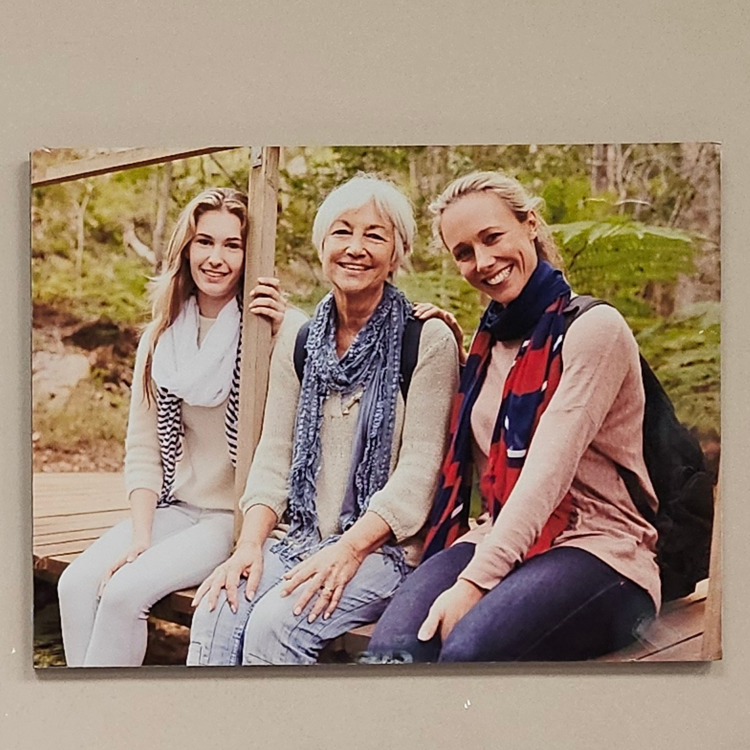 Three women smiling outdoors on wooden bridge